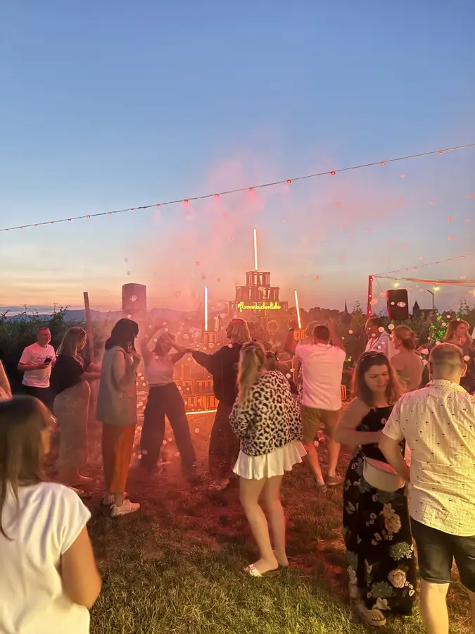 Feiernde Gäste unter Lichterketten am Abend