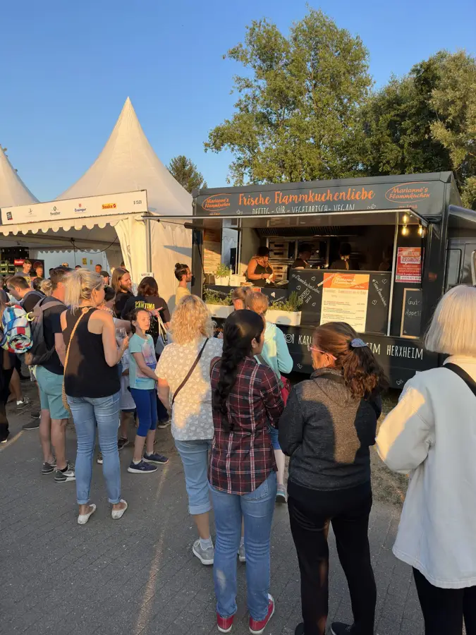 Gäste stehen am Foodtruck bei einem Fest mit Pavillons an
